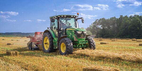 farmer in tractor baling hay