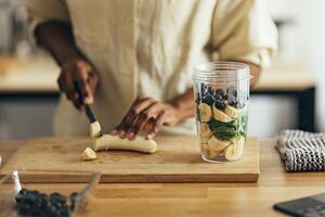 person chopping banana for smoothie