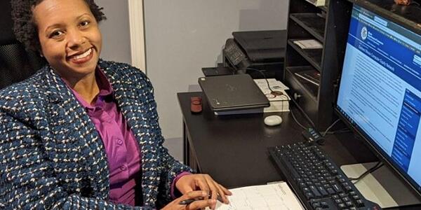 older woman sitting at desk with pad and computer