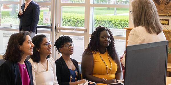 group of 4 young adults in a meeting with a speaker