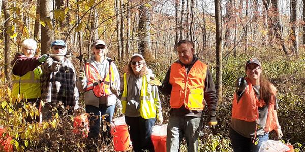 volunteers with orange buckets in forest