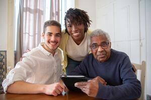 three people smiling while looking at tablet