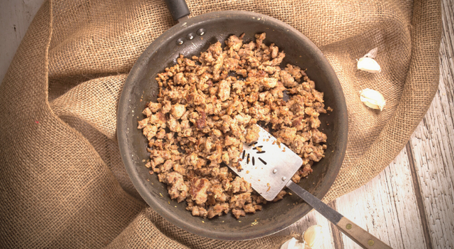 Image of a pan with ground meat and a spatula on burlap fabric