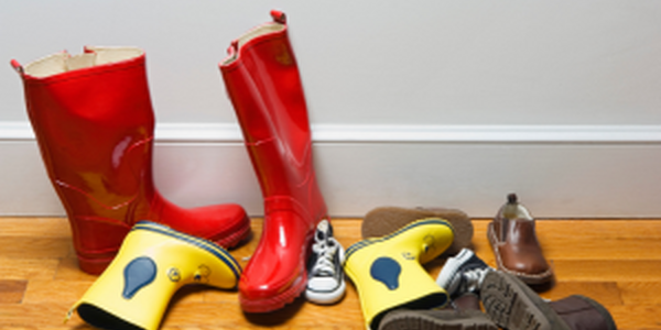 Pairs of shoes tossed in hallway with wood floor.