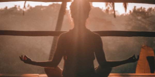 Women meditating in front of sunset